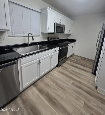 a kitchen with stainless steel appliances granite countertop a sink stove microwave and refrigerator