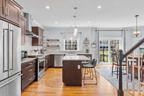 a kitchen with stainless steel appliances granite countertop a stove top oven a sink dishwasher a dining table and chairs with wooden floor