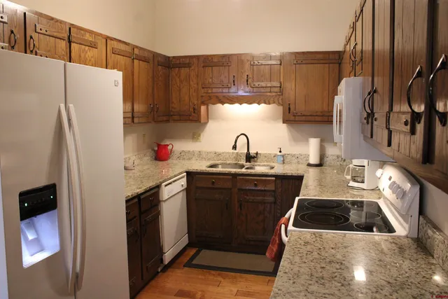 a kitchen with granite countertop a refrigerator a sink and wooden cabinets