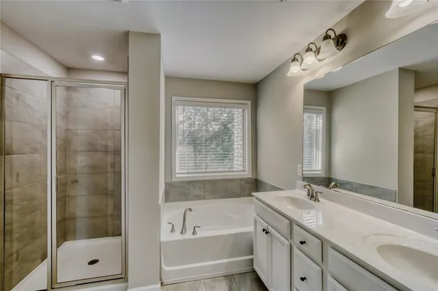 a bathroom with a tub sink shower and mirror