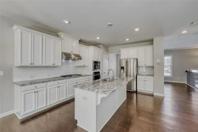 a large kitchen with stainless steel appliances and white cabinets
