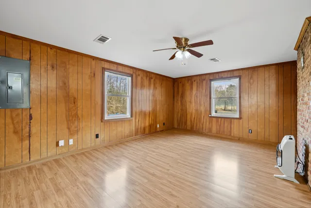 a view of empty room with wooden floor and fan