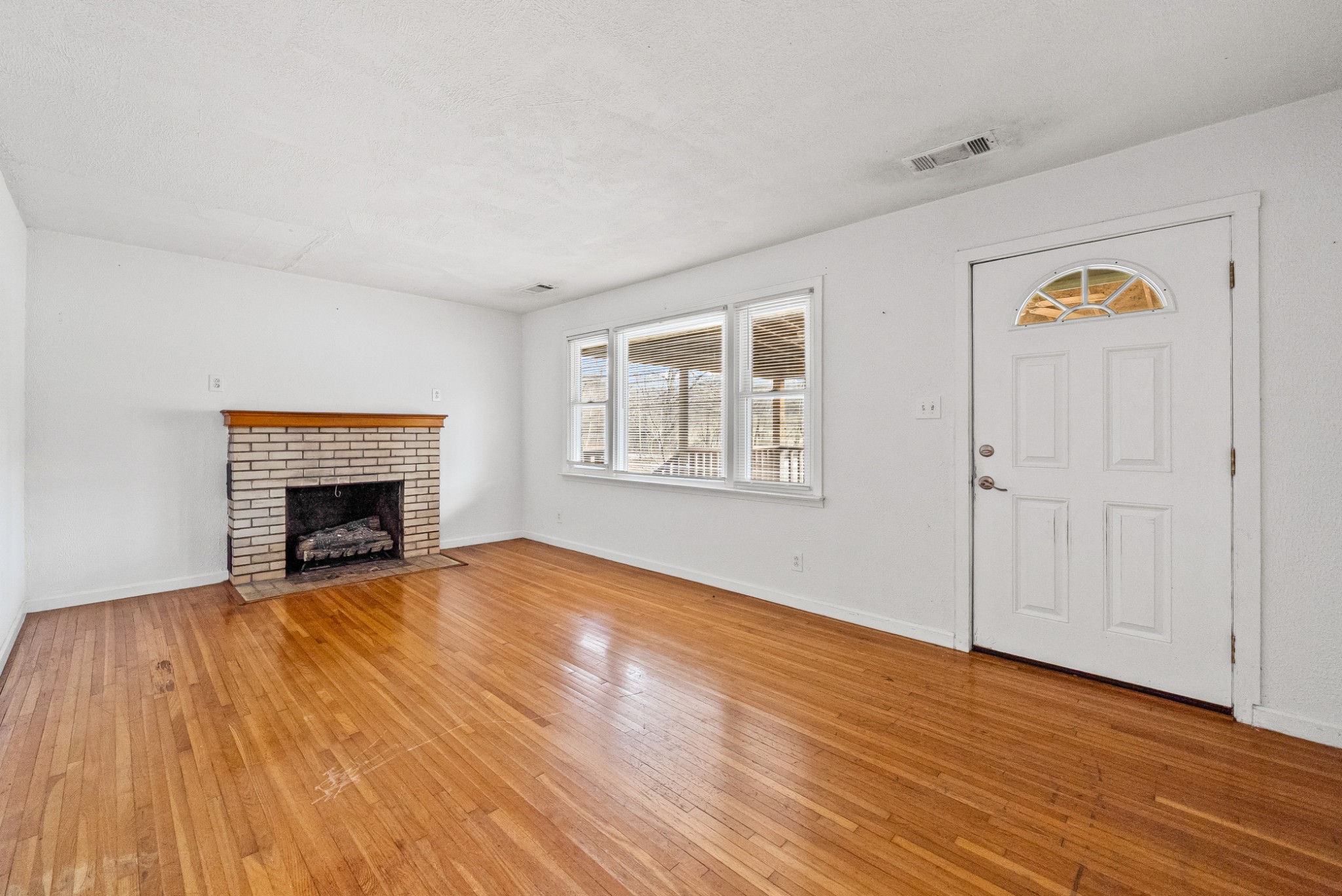 1667 McWhorter Road Cunningham, TN 37052 - Photo 7 of 35 an empty room with wooden floor fireplace and windows