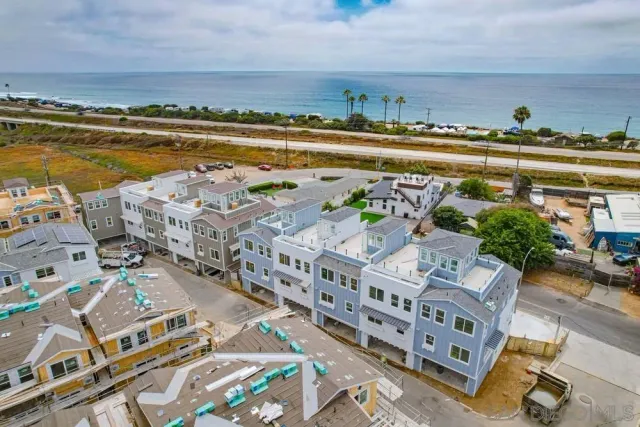 an aerial view of a city with lots of residential buildings and ocean view in back