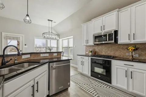 a kitchen with stainless steel appliances granite countertop a sink a stove a microwave and cabinets