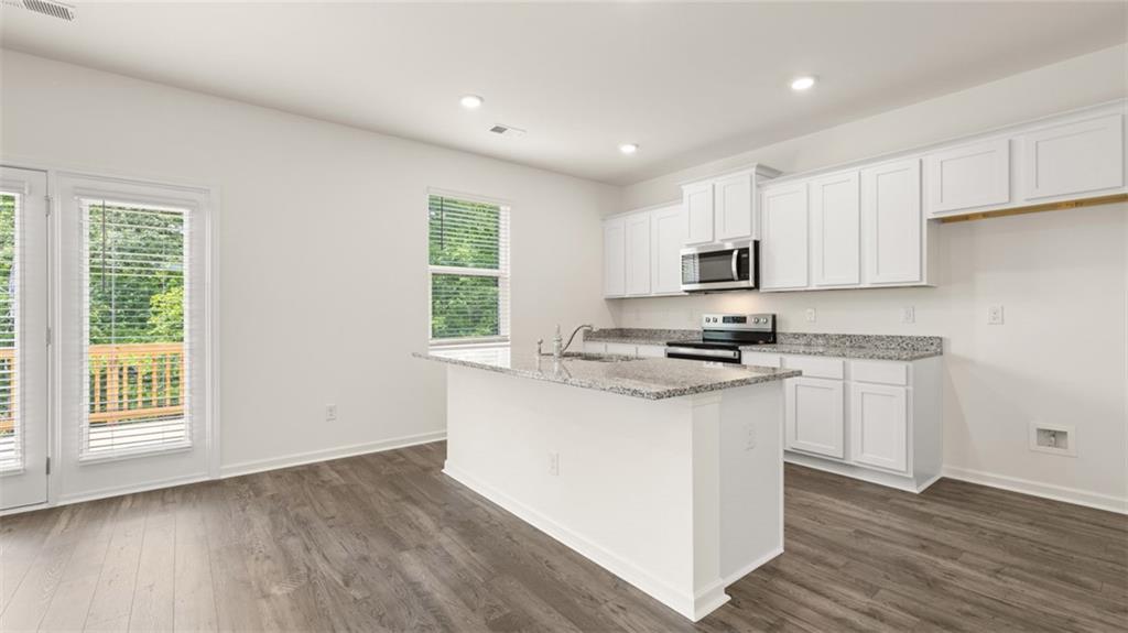 621 Lobelia Way Locust Grove, GA 30248 - Photo 13 of 42 a kitchen with granite countertop a stove a sink and a microwave