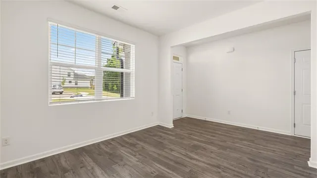 an empty room with wooden floor mirror and windows