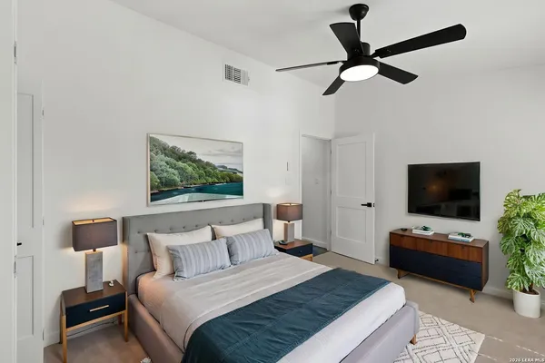 a bedroom with bed a flat tv screen and a chandelier
