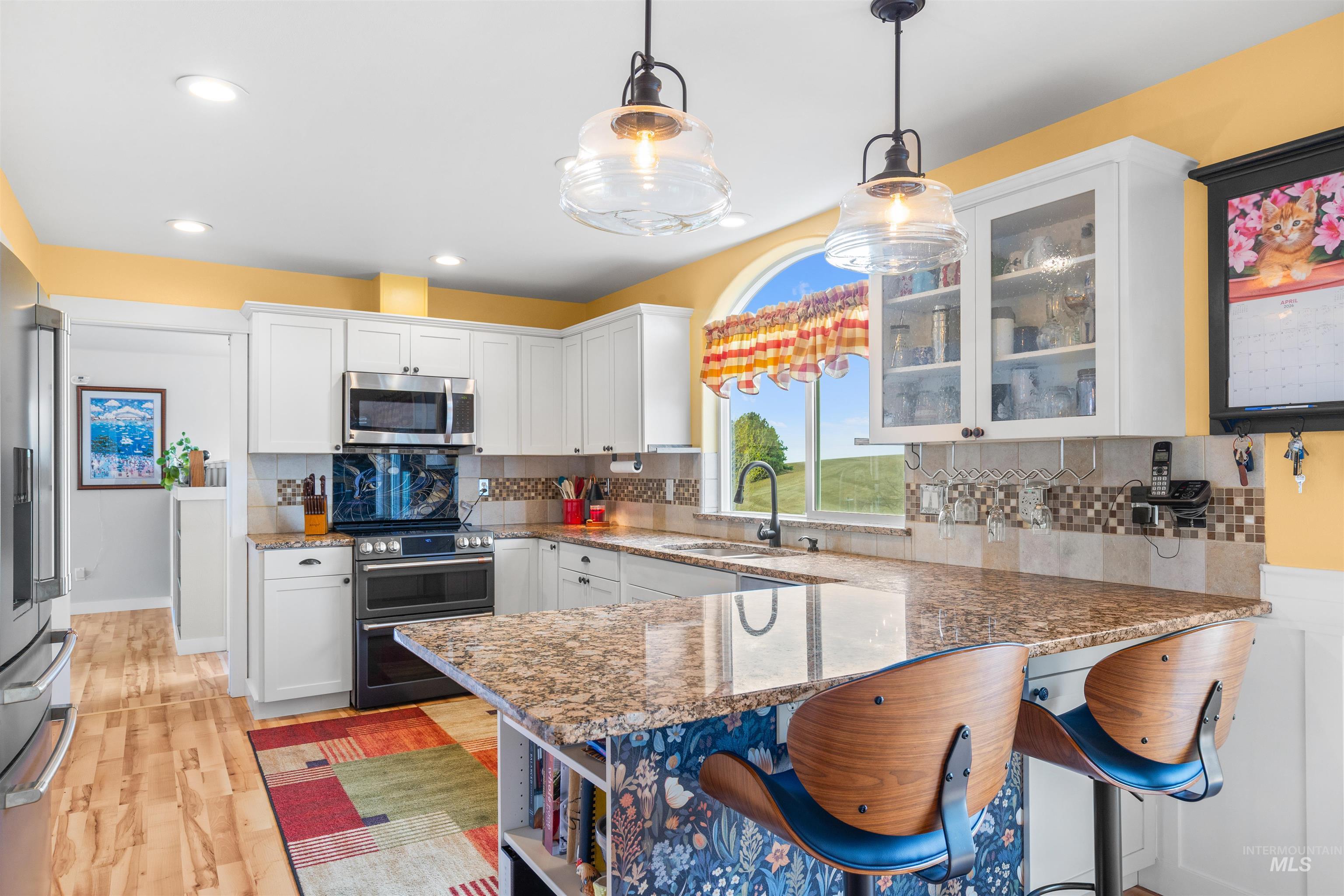 2435 Arborcrest Road Moscow, ID 83843 - Photo 11 of 48 Kitchen featuring a peninsula, dark stone counters, a breakfast bar area, white cabinetry, and glass insert cabinets