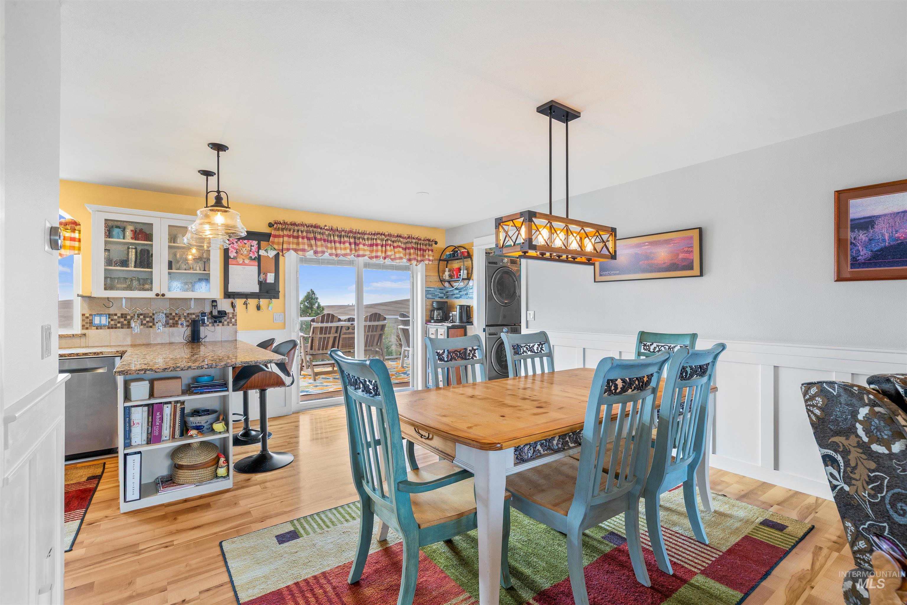 2435 Arborcrest Road Moscow, ID 83843 - Photo 15 of 48 Dining space featuring stacked washing machine and dryer, a wainscoted wall, a decorative wall, and light wood-style flooring