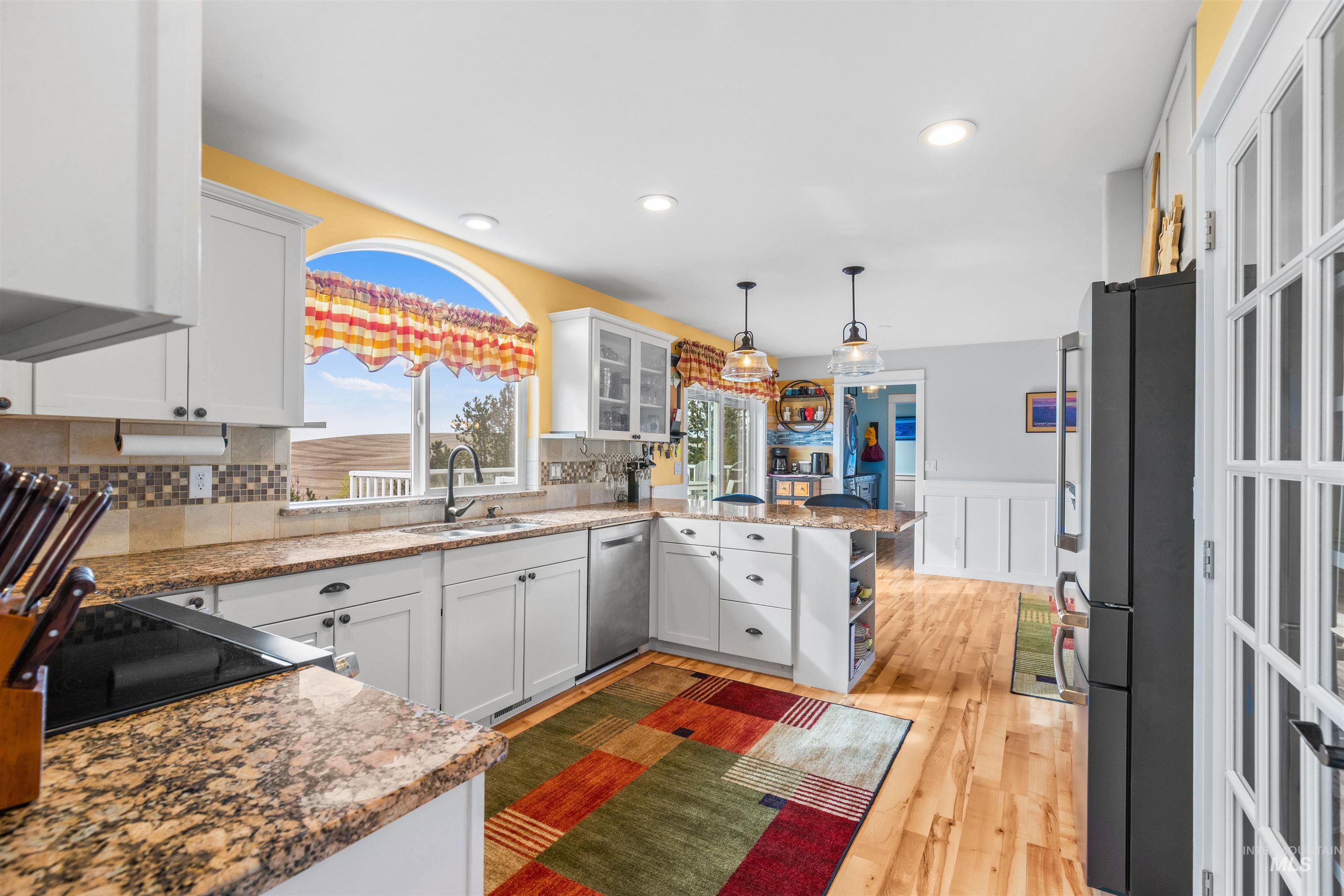 2435 Arborcrest Road Moscow, ID 83843 - Photo 9 of 48 Kitchen featuring a peninsula, white cabinets, wainscoting, glass fronted cabinets, and dark stone counters