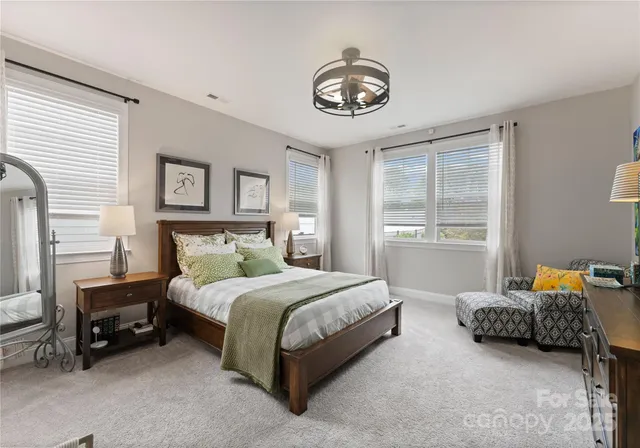 a spacious bedroom with a bed a chandelier and a window
