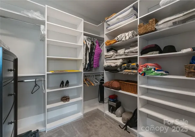 a view of walk in closet with clothes and shoes