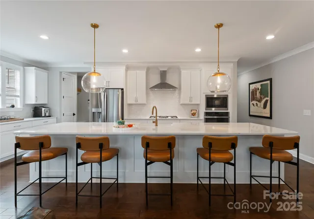 a kitchen with stainless steel appliances granite countertop a dining table chairs sink and stove top oven