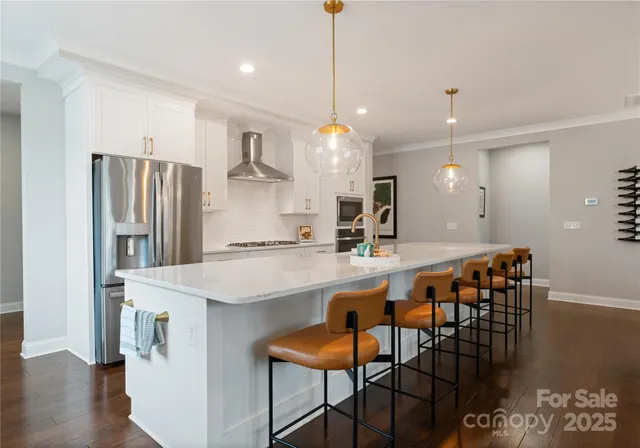 a kitchen with stainless steel appliances granite countertop a dining table chairs refrigerator and sink