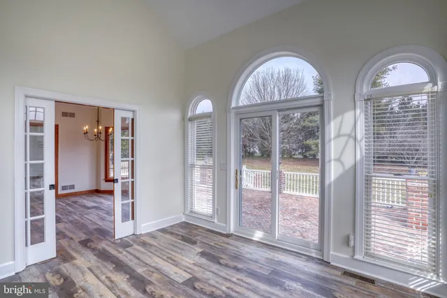 an empty room with chandelier fan and windows