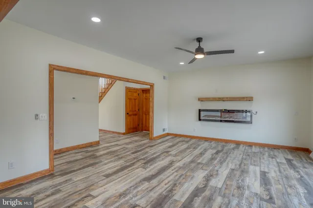an empty room with chandelier fan and windows