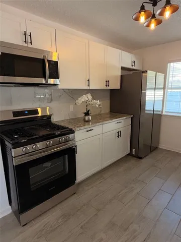 a kitchen with stainless steel appliances a stove a microwave and white cabinets