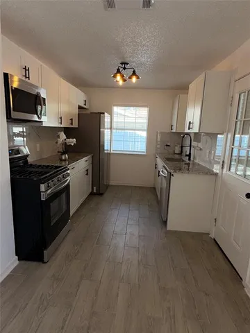 a kitchen with granite countertop a stove top oven a sink dishwasher and a refrigerator