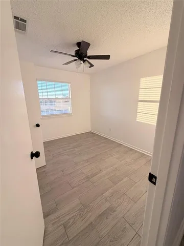 an empty room with windows and fan