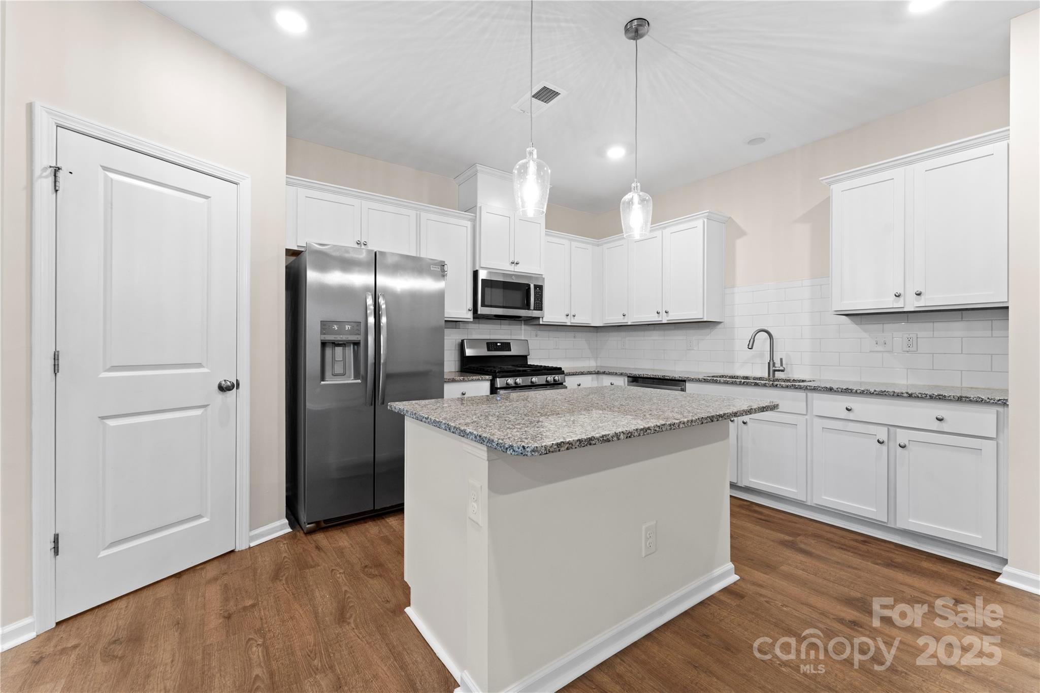 5215 Maynard Hl Drive Monroe, NC 28110 - Photo 8 of 34 a kitchen with stainless steel appliances granite countertop a refrigerator a sink dishwasher a stove and white cabinets with wooden floor