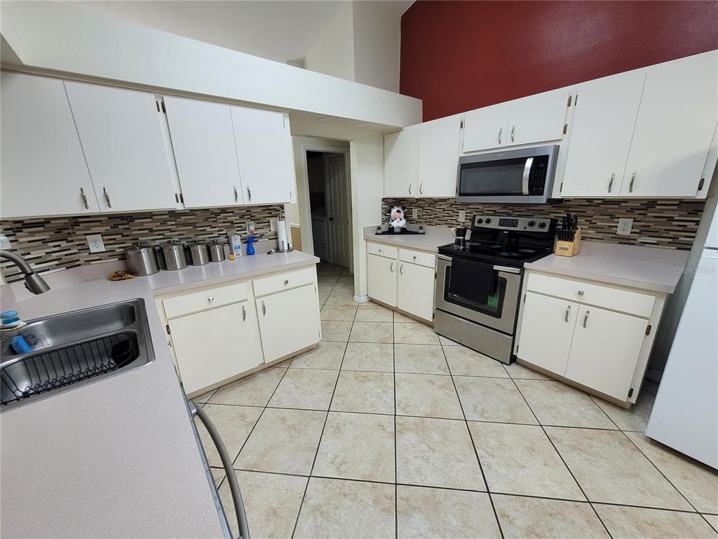 4233 Amber Ridge Lane Valrico, FL 33594 - Photo 12 of 40 a kitchen with white cabinets a sink and white appliances