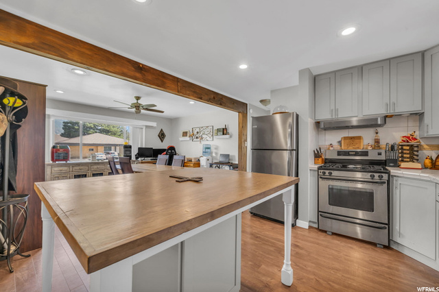 4783 South 200 East Washington Terrace, UT 84405 - Photo 1 of 1 Kitchen with stainless steel appliances, white cabinets, light countertops, light hardwood flooring, backsplash, and ceiling fan