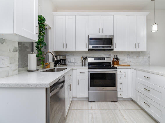 a kitchen with stainless steel appliances white cabinets and a stove top oven