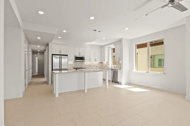 a large white kitchen with white cabinets and stainless steel appliances