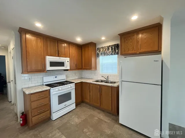 a kitchen with stainless steel appliances granite countertop a refrigerator a stove a sink and a microwave