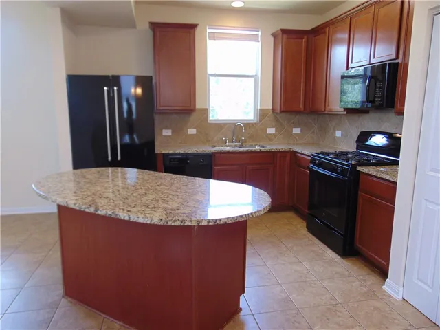 a kitchen with stainless steel appliances granite countertop a stove a sink a microwave and a refrigerator