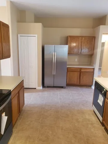 a view of a refrigerator in kitchen and an empty room