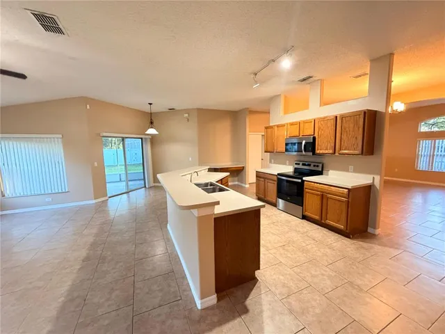 a kitchen with stainless steel appliances granite countertop a stove top oven a sink and a refrigerator