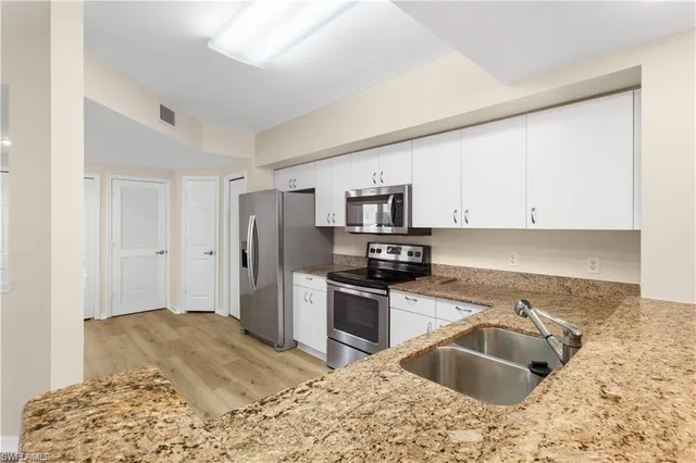 a kitchen with granite countertop a sink stove and refrigerator