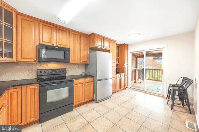 a kitchen with stainless steel appliances granite countertop a refrigerator stove top oven dining table and chairs
