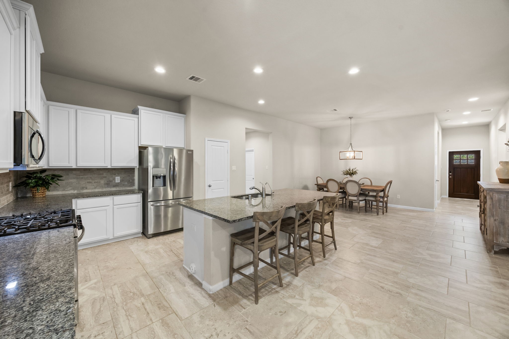 519 Yellow Bullhead Court Rosenberg, TX 77469 - Photo 7 of 24 a kitchen with stainless steel appliances a refrigerator a stove a sink a dining table and chairs with wooden floor