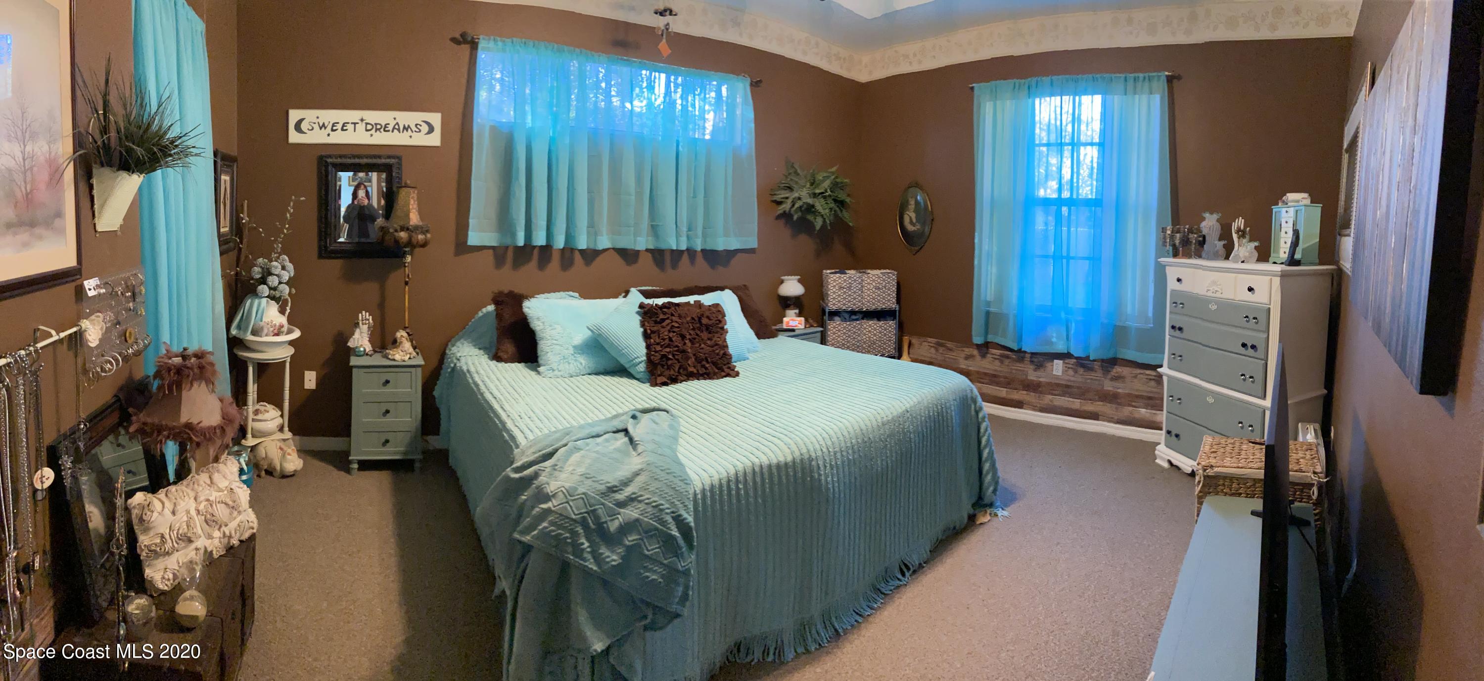 3150 Aurora Road Melbourne, FL 32934 - Photo 6 of 8 a bedroom with a bed and a mirror
