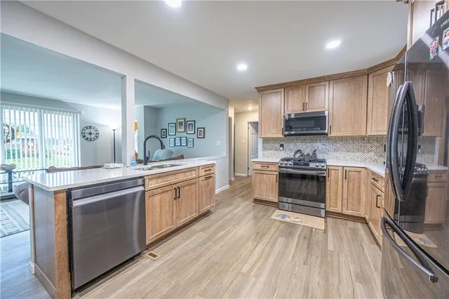 a kitchen with stainless steel appliances kitchen island granite countertop a stove a sink and a refrigerator