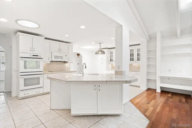 a kitchen with kitchen island granite countertop white cabinets and white appliances