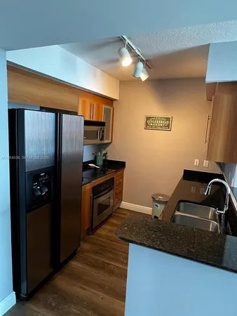 a kitchen with granite countertop a refrigerator and a sink