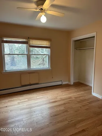 an empty room with wooden floor fan and windows