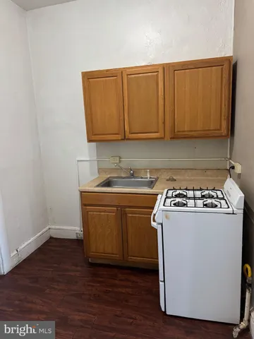 a kitchen with granite countertop a sink a stove and cabinets