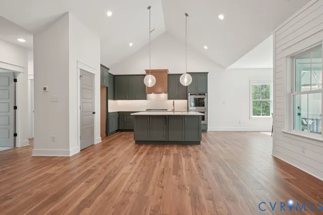 a living room with kitchen island granite countertop wooden floor and a sink