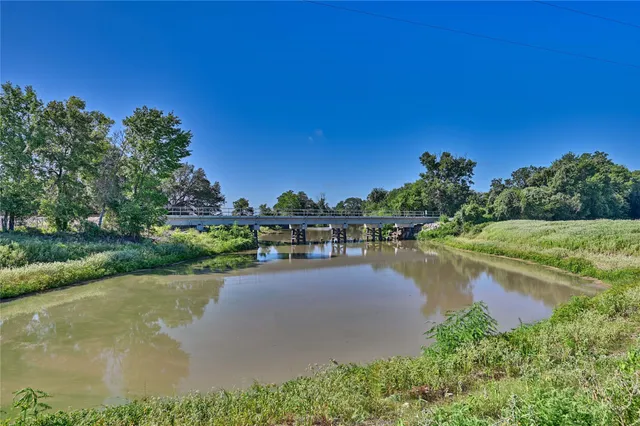 a view of a lake with a yard and large trees