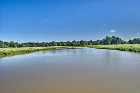 a view of a lake with a yard and large trees