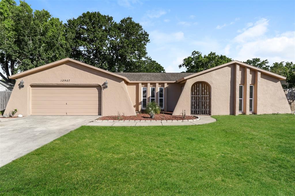 12907 Cedar Ridge Drive Hudson, FL 34669 - Photo 1 of 21 a view of a white house with a yard and sitting area