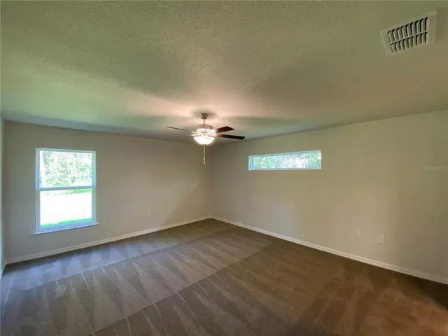 an empty room with a window and a ceiling fan