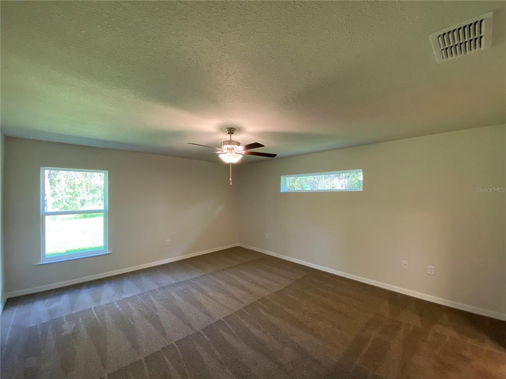 16090 Southwest 55th Avenue Road Ocala, FL 34473 - Photo 14 of 28 an empty room with a window and a ceiling fan