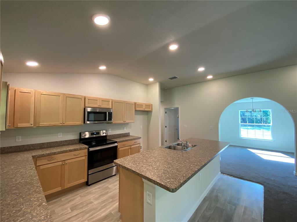 16090 Southwest 55th Avenue Road Ocala, FL 34473 - Photo 8 of 28 a kitchen with kitchen island granite countertop stainless steel appliances a sink a stove a counter top space and cabinets
