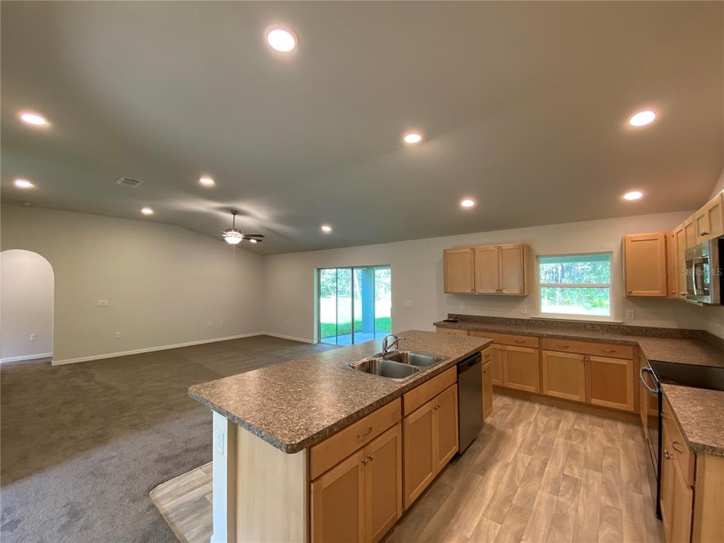 16090 Southwest 55th Avenue Road Ocala, FL 34473 - Photo 10 of 28 a large kitchen with stainless steel appliances a large counter top a stove a sink a refrigerator and a cabinets